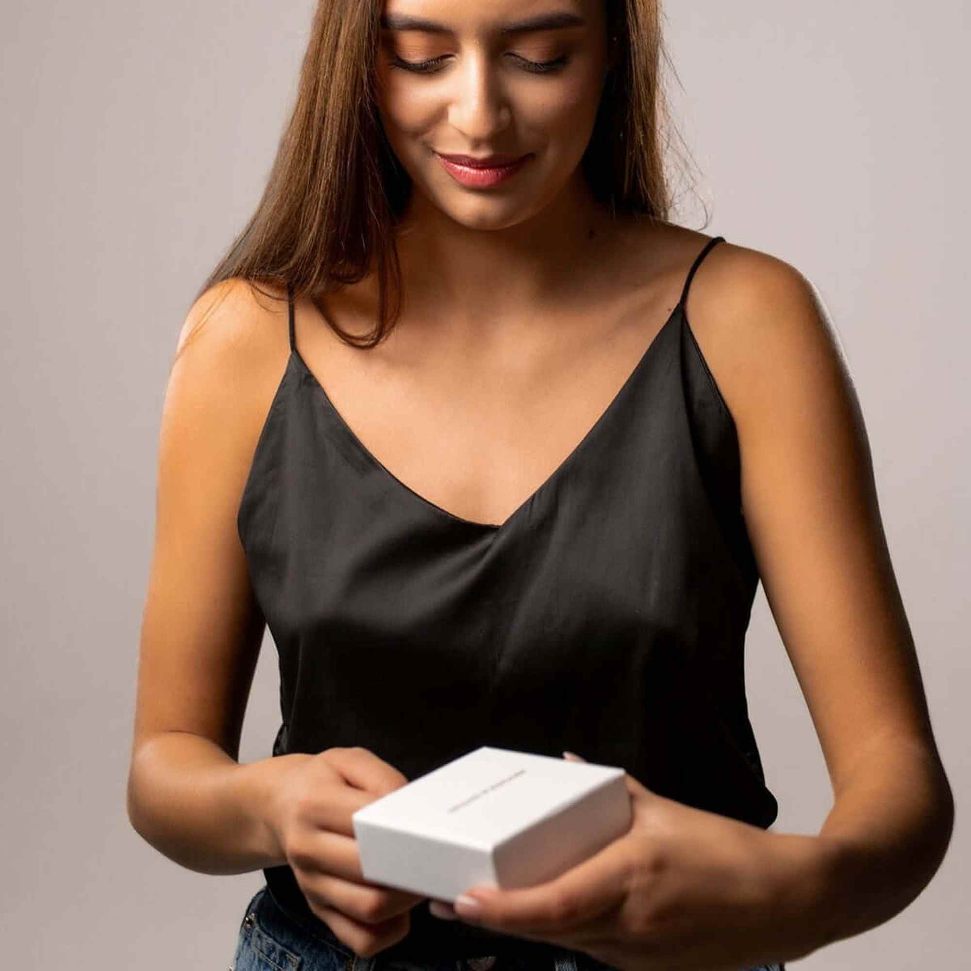 Woman opening a gift box, revealing the Love Photo Necklace by Brother & Sisters, showcasing personalized elegance.