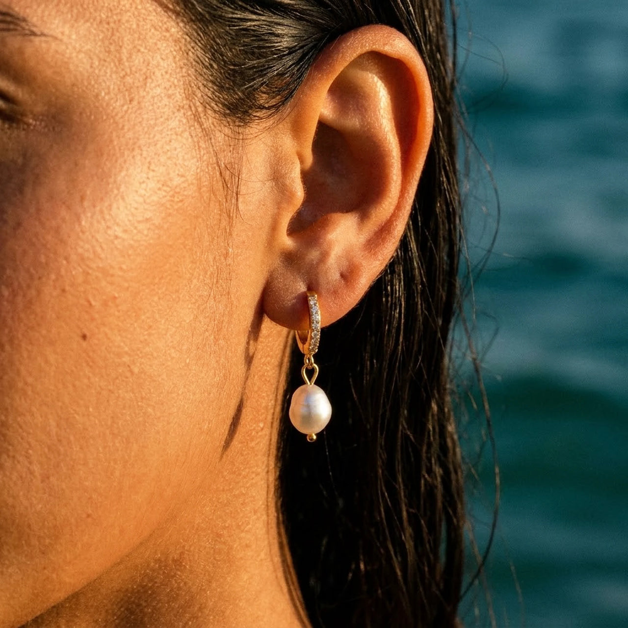 Pearl Drop Huggie Hoops in Gold, close-up on the earlobe | SKU: 41003-gold
