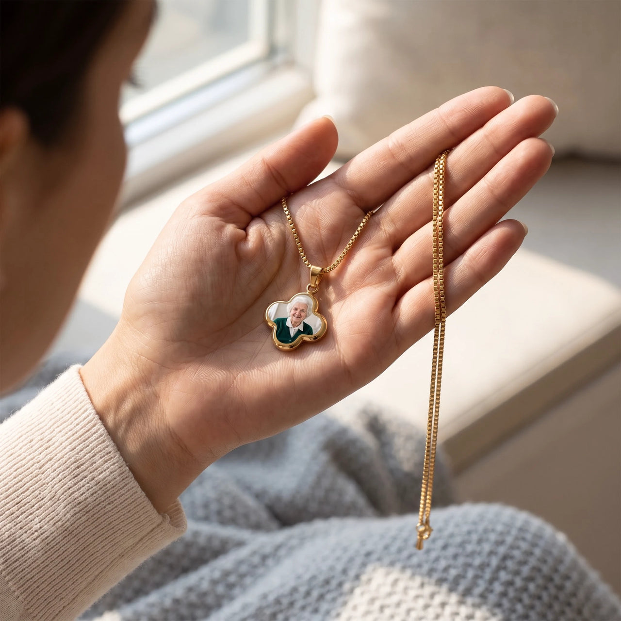 The gold clover photo pendant with a grandmother's photo in an open palm, showing its real small size | SKU: TPH-CLVN-GOLD