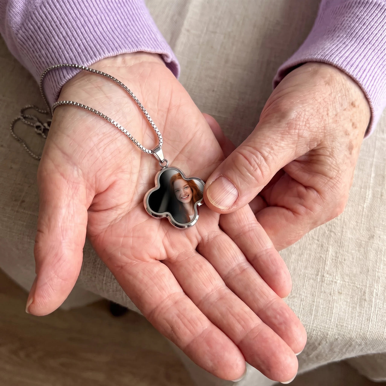 Thumb warming the silver clover pendant: the hidden photo appears under the thumb while the rest stays black | SKU: TPH-CLVN-SILVER