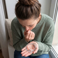 Thumbnail for Moved woman looking down at the silver Secret Cushion Photo Bracelet in her palm, her grandmother's photo revealed in the plate | SKU: TPH-CUSB-SILVER