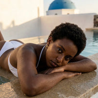 Thumbnail for Tiny Huggie Hoops in Gold, worn by a pool in Santorini | SKU: 41002-gold