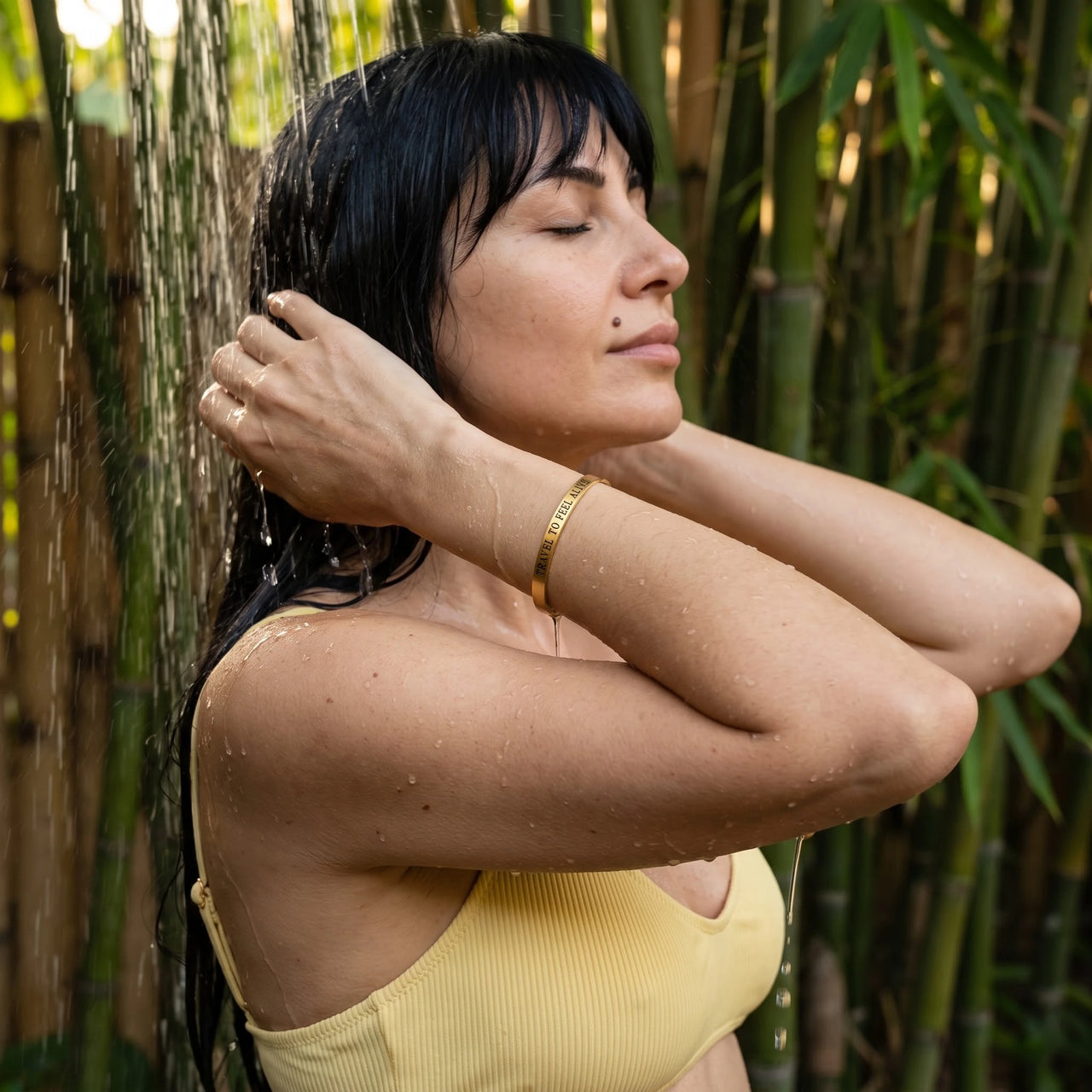 Travel To Feel Alive bracelet in gold worn in an outdoor shower | SKU: ttfa-g